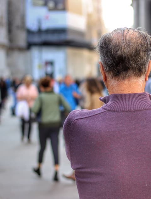 Ein älterer Mann Schaut Auf Eine Verschwommene Menschenmenge